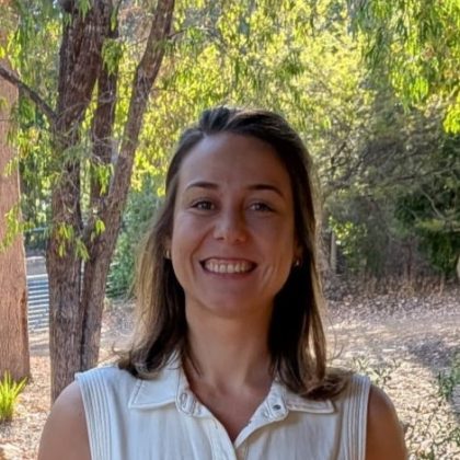Dr Lauren Egan smiles at the camera. She has medium length dark hair and is wearing a white sleeveless shirt