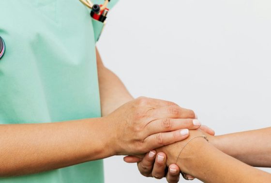 Close up of a doctor supporting a patient by cradling their hands
