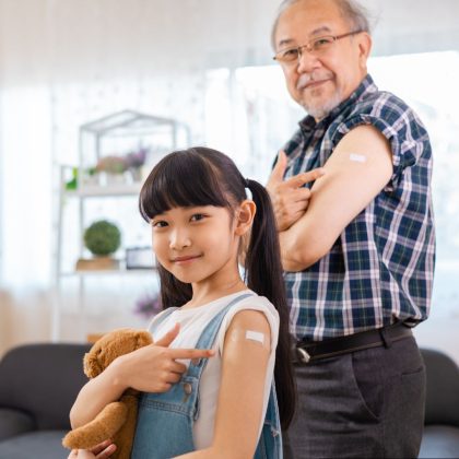 Elderly Man and Little Girl Pointing at Their Vaccinated Arm